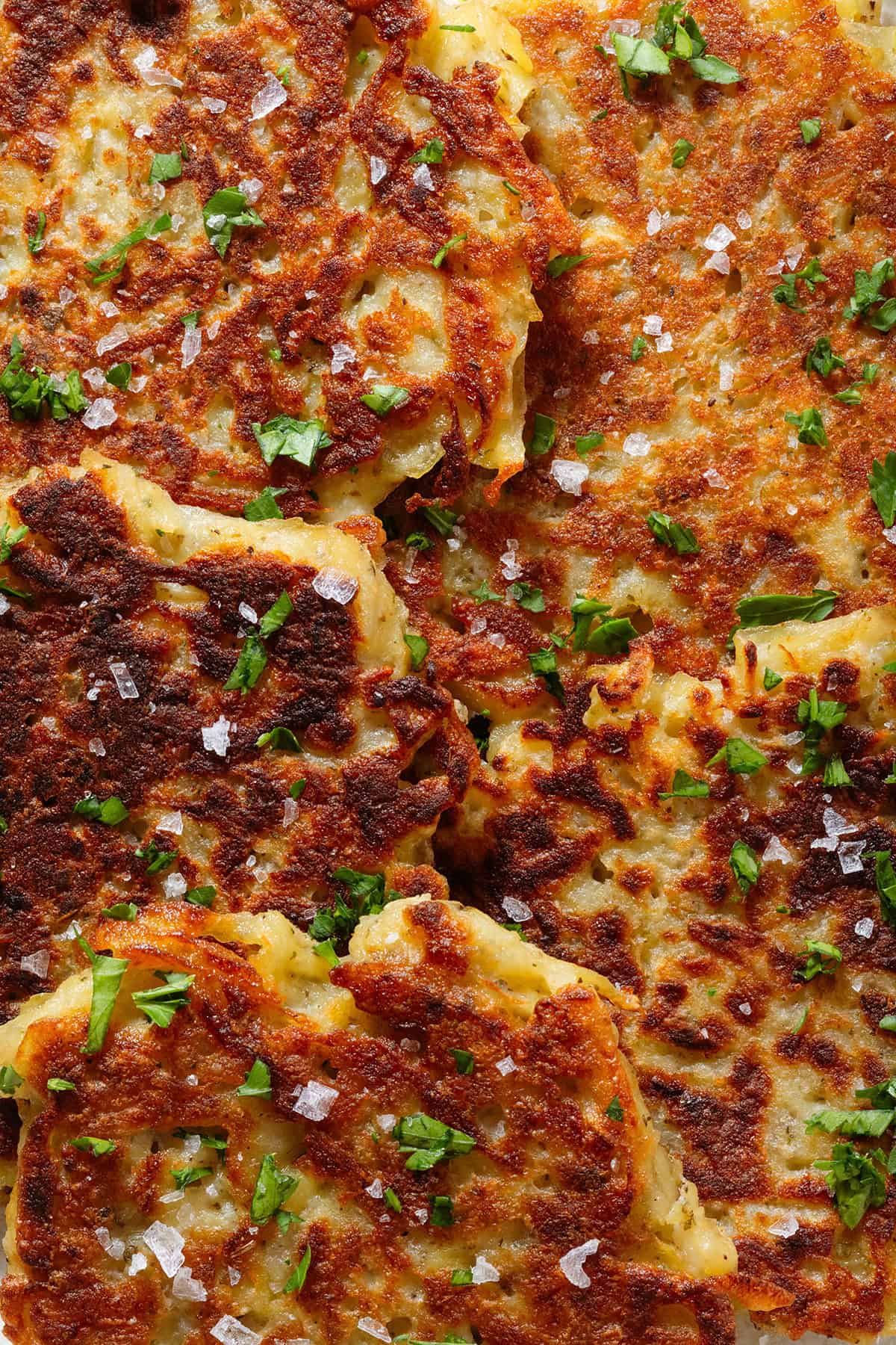 Golden brown potato fritters sprinkled with finely chopped fresh parsley and flaky sea salt.
