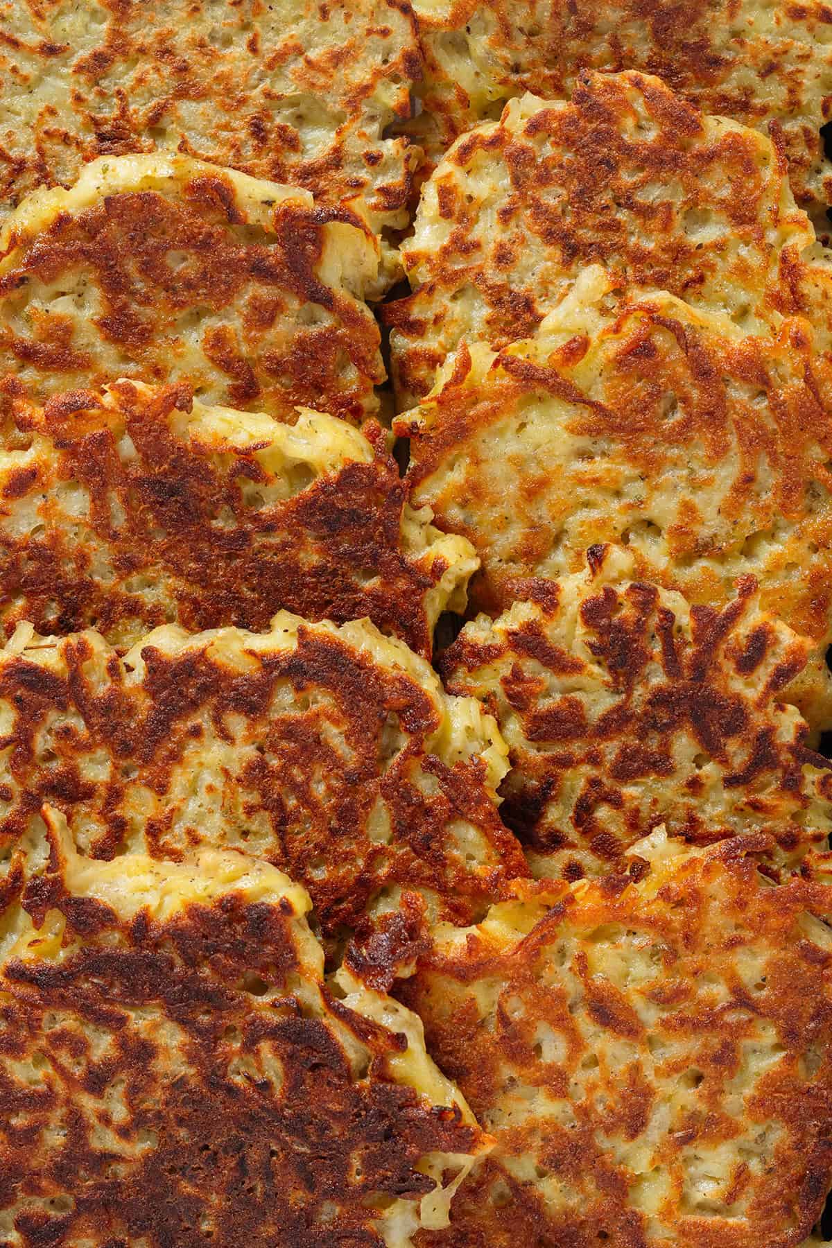 Golden brown potato fritters overlapping each other shown from overhead.