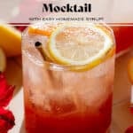 A short glass with bright red hibiscus mocktail topped with sparkling water and garnished with a slice of orange and lemon.