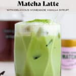 A matcha latte with cold foam on top dusted with matcha for garnish and a glass straw.