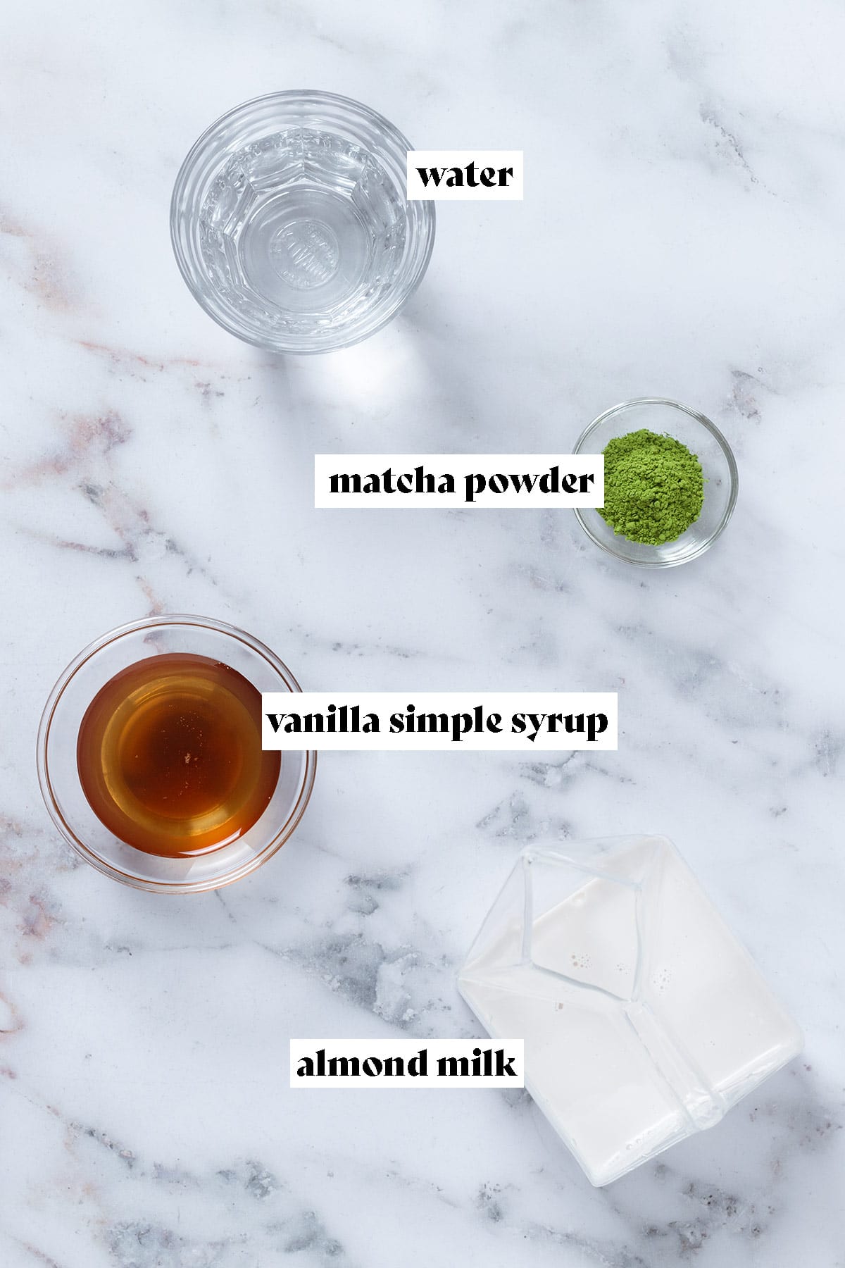 Water, almond milk, matcha powder, and vanilla syrup laid out in small bowls with text overlay.