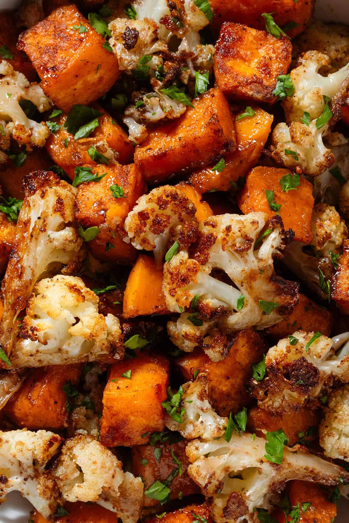 Caramelized roasted cauliflower florets and diced sweet potato garnished with finely chopped fresh parsley.