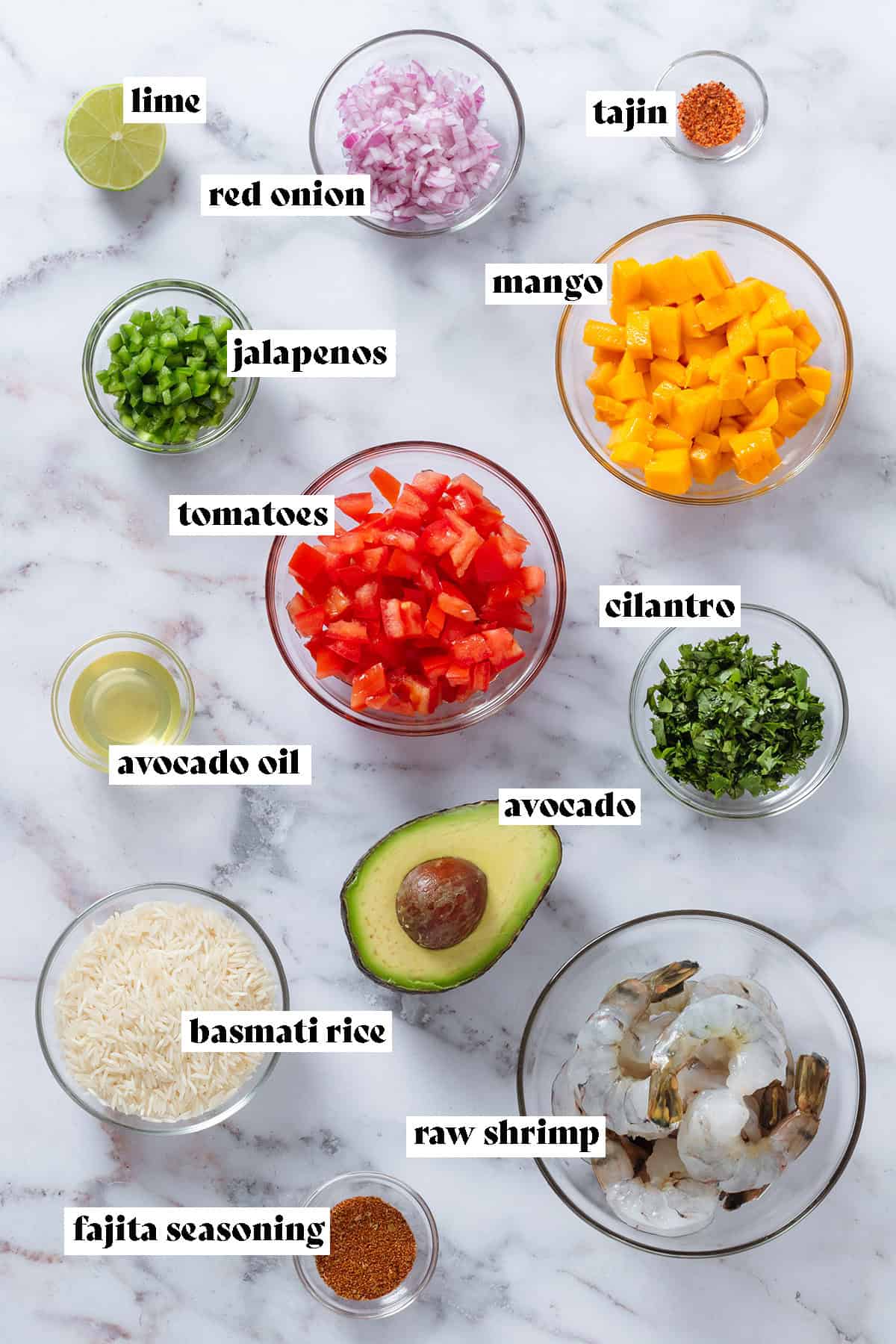 Raw shrimp, diced tomatoes, mango, red onion, and other ingredients in small glass bowls.