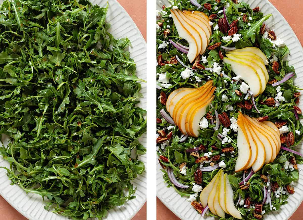 Arugula tossed with dressing on a large white platter on the left and topped with sliced pears, red onion, pecans, and feta on the right.