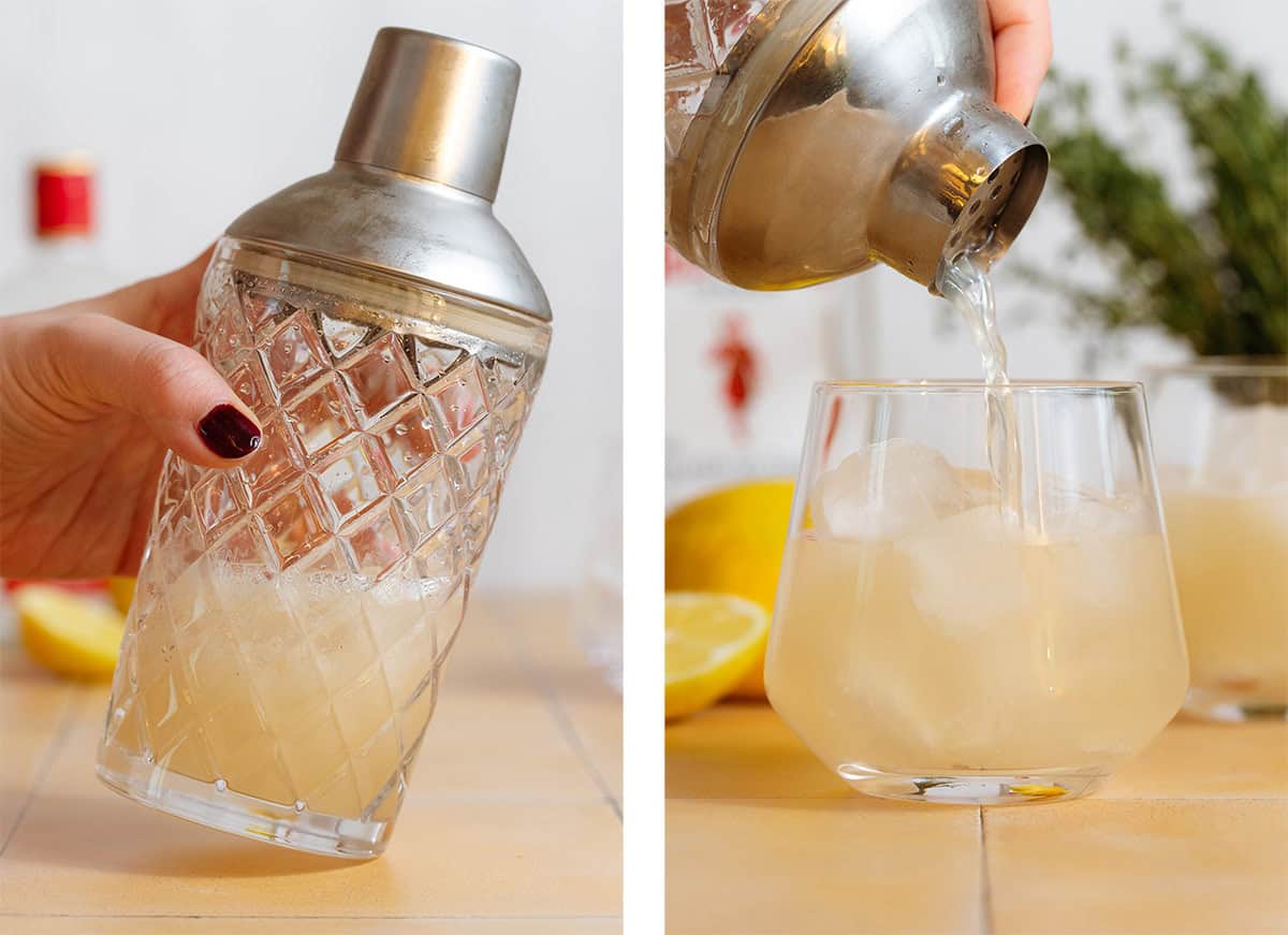 Cocktail being strained from a glass shaker into a short glass over ice.