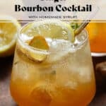 Sparkling ginger bourbon cocktail in a short glass with ice topped with a slice of lemon, fresh ginger, fresh thyme, and a gold metal straw.