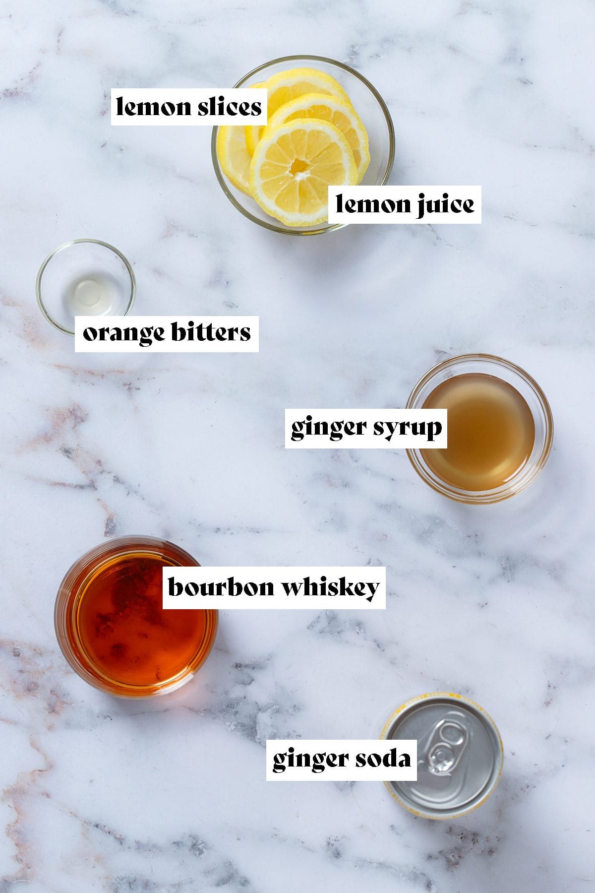 Bourbon, ginger soda, ginger syrup, bitters, and lemon slices in bowls laid out on a marble background with text overlay.