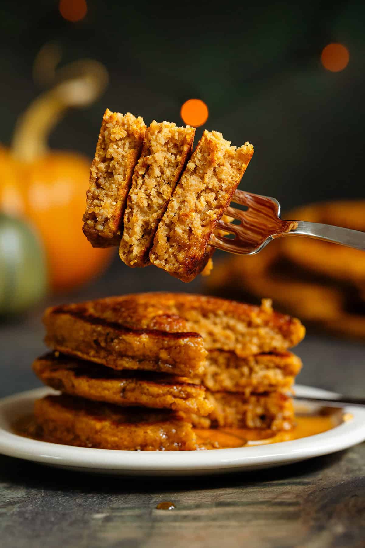 A fork holding a cut out of 3 pancakes to show the fluffy inside.