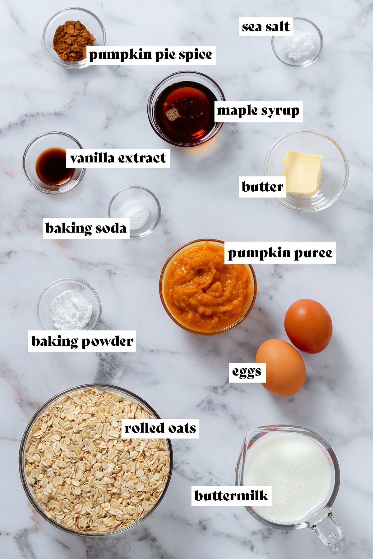 Ingredients like oats, pumpkin puree, buttermilk, butter, maple syrup, vanilla, spices, and other ingredients in small glass bowls with text overlay.
