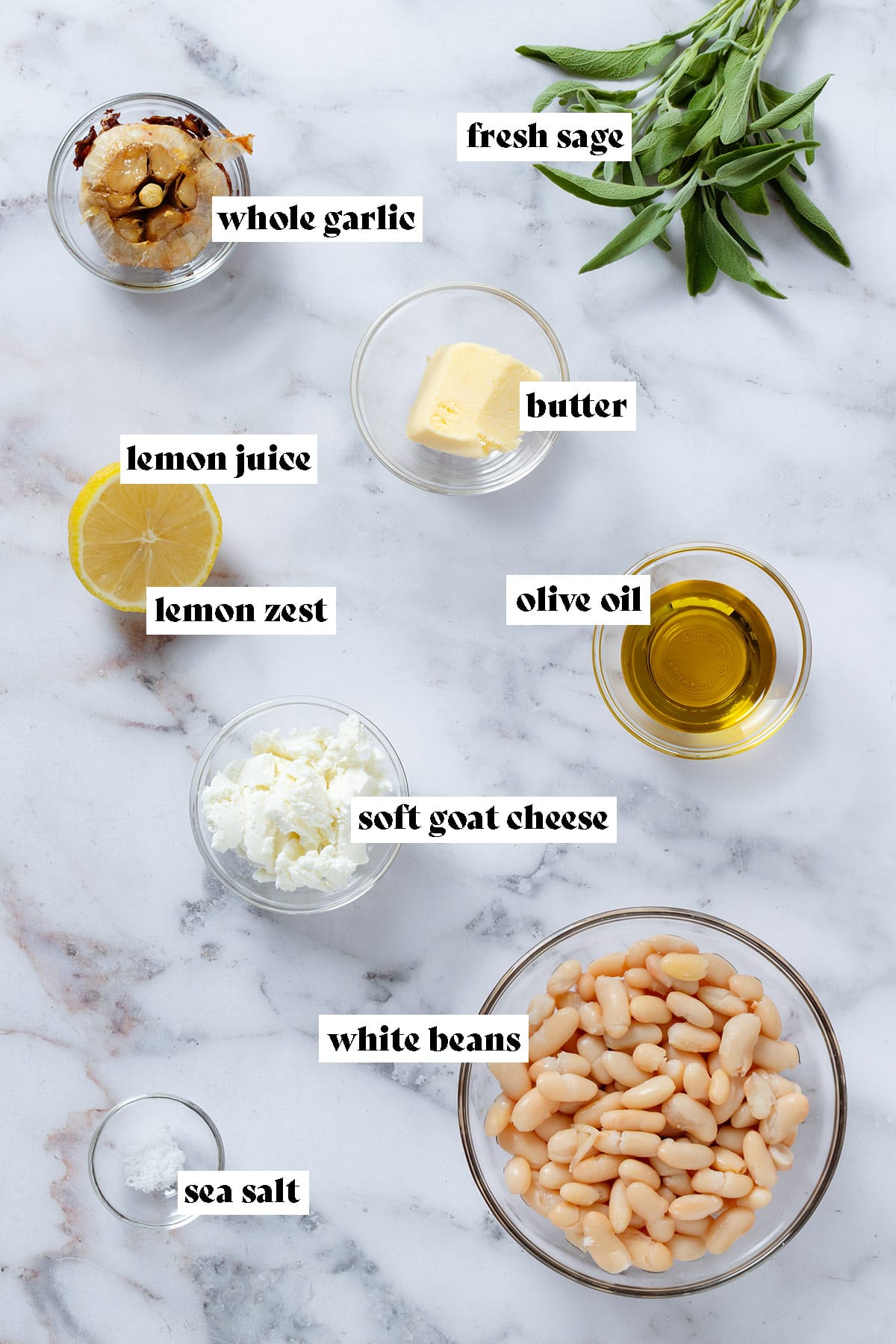 Ingredients like cooked white beans, olive oil, goat cheese, butter, sage, and garlic in small glass bowls.