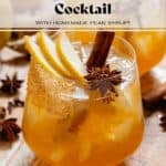 A deep orange pear cocktail in a short glass with ice and a coarse sugar rim, garnished with sliced pear, a cinnamon stick, star anise, and cloves.