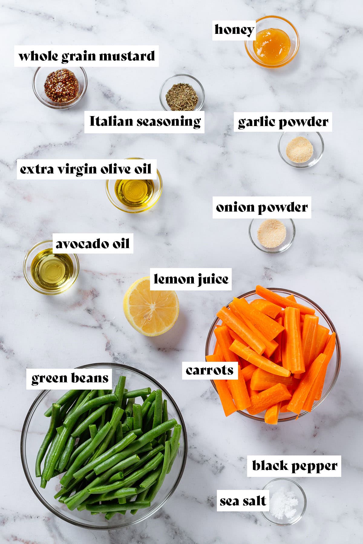 Ingredients in glass bowls like green beans, chopped carrots, avocado oil, honey, spices, and whole grain mustard.