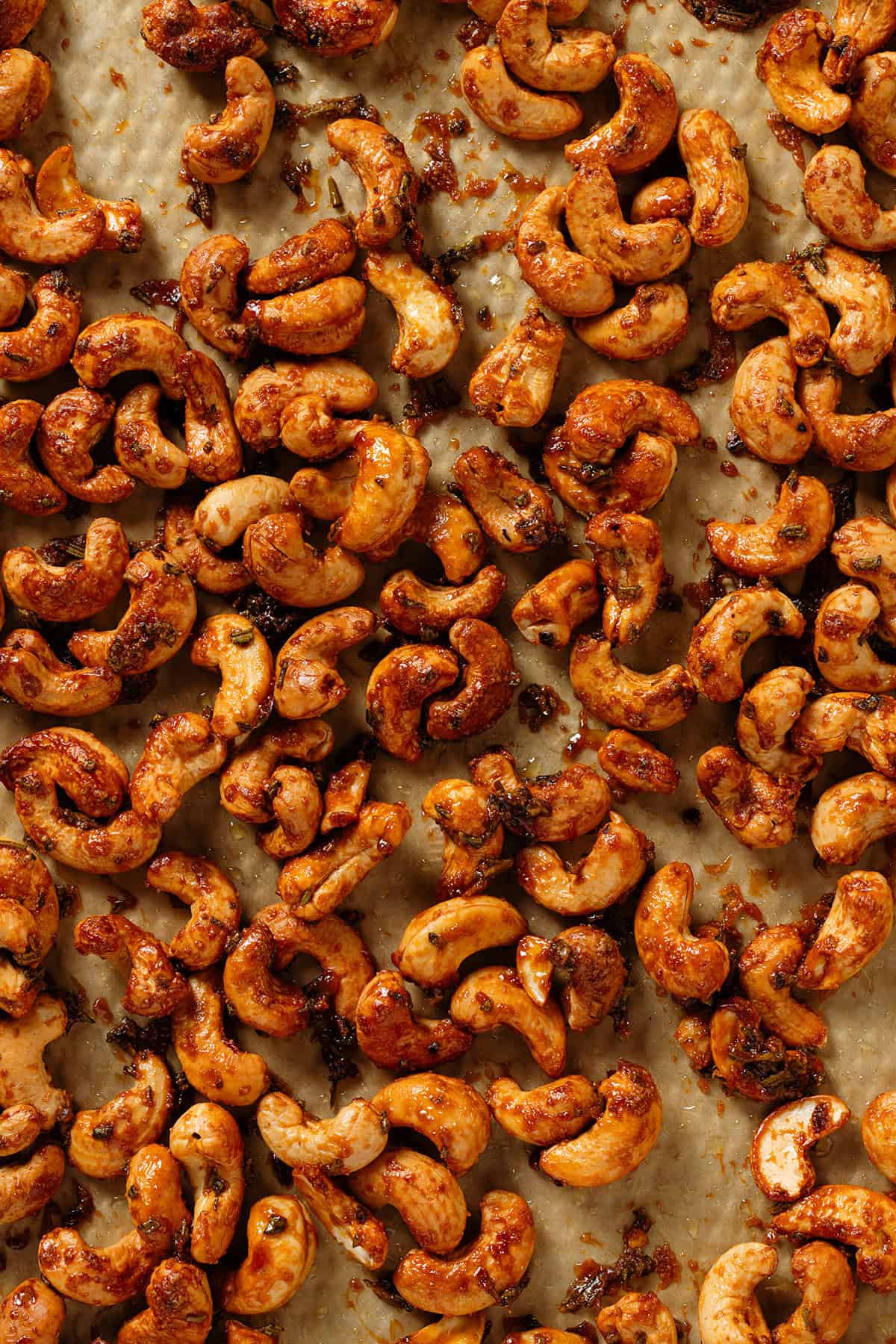 Roasted golden caramelized cashews ona baking sheet lined with parchment paper.