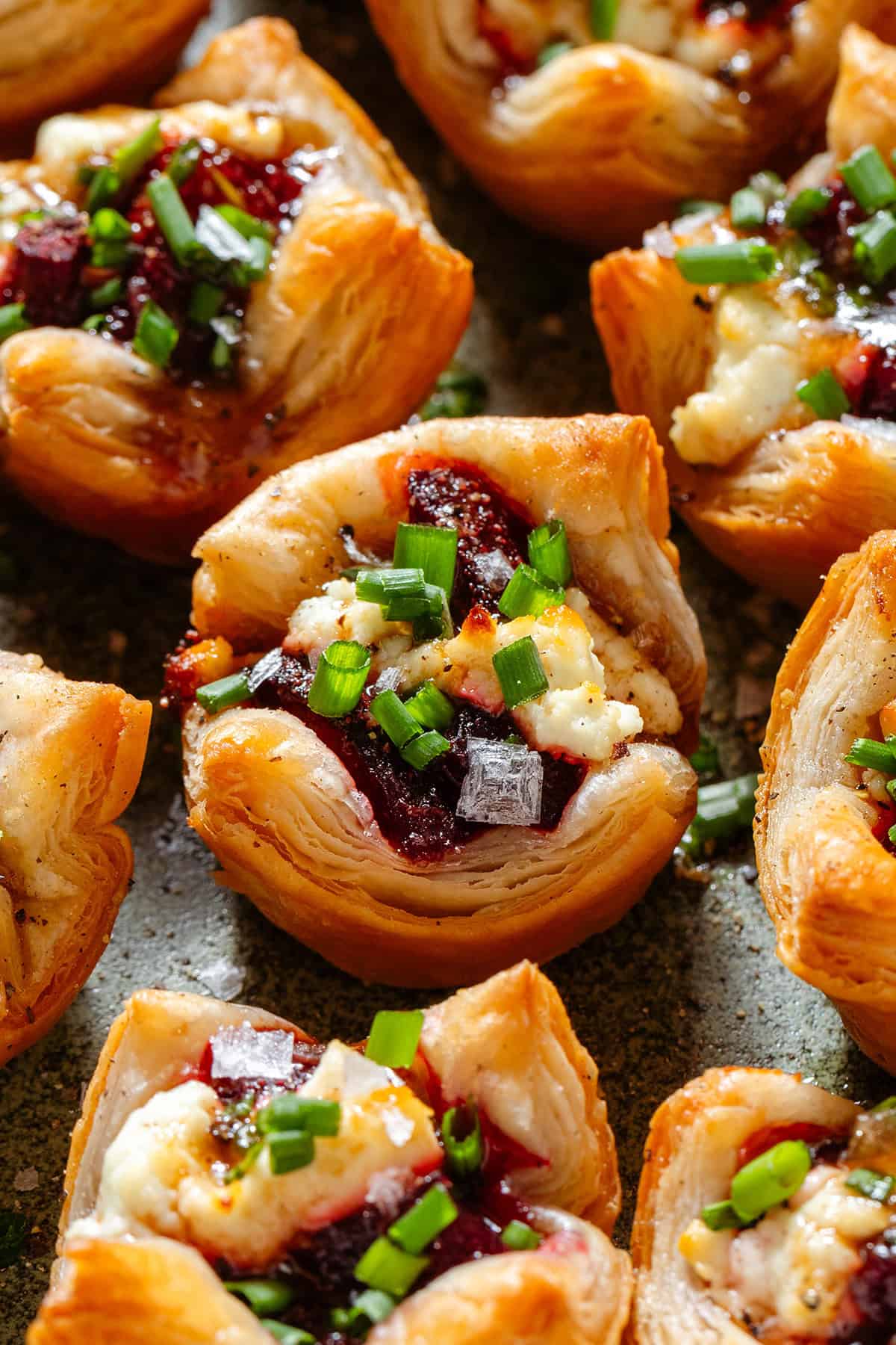 Small puff pastry cups with cooked beets and goat cheese topped with flaky sea salt, chopped chives, and balsamic vinaigrette.