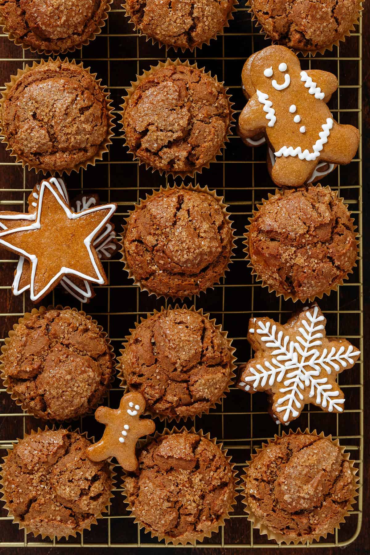 Gingerbread muffins on a gold cooling rack with gingerbread cookies in between them.