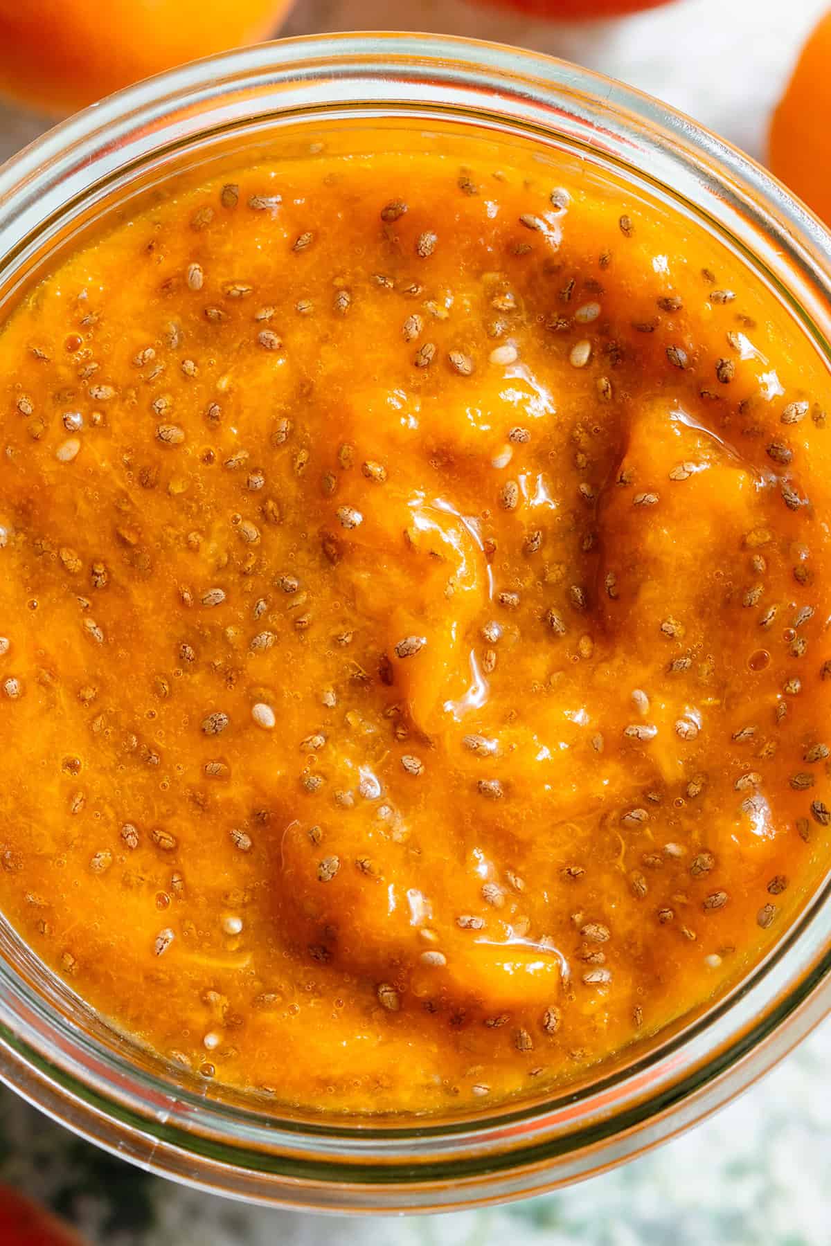 Bright orange apricot chia jam in a glass jar.