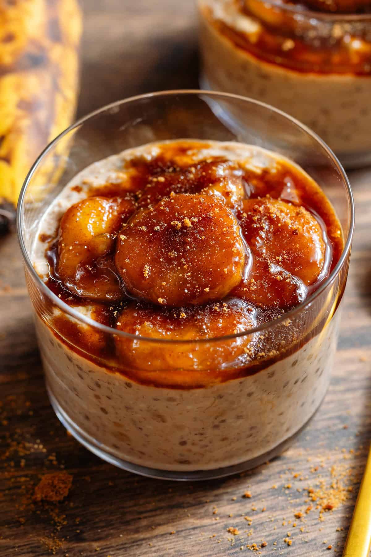 A short glass with brown sugar overnight oats topped with caramelized banana and more brown sugar.