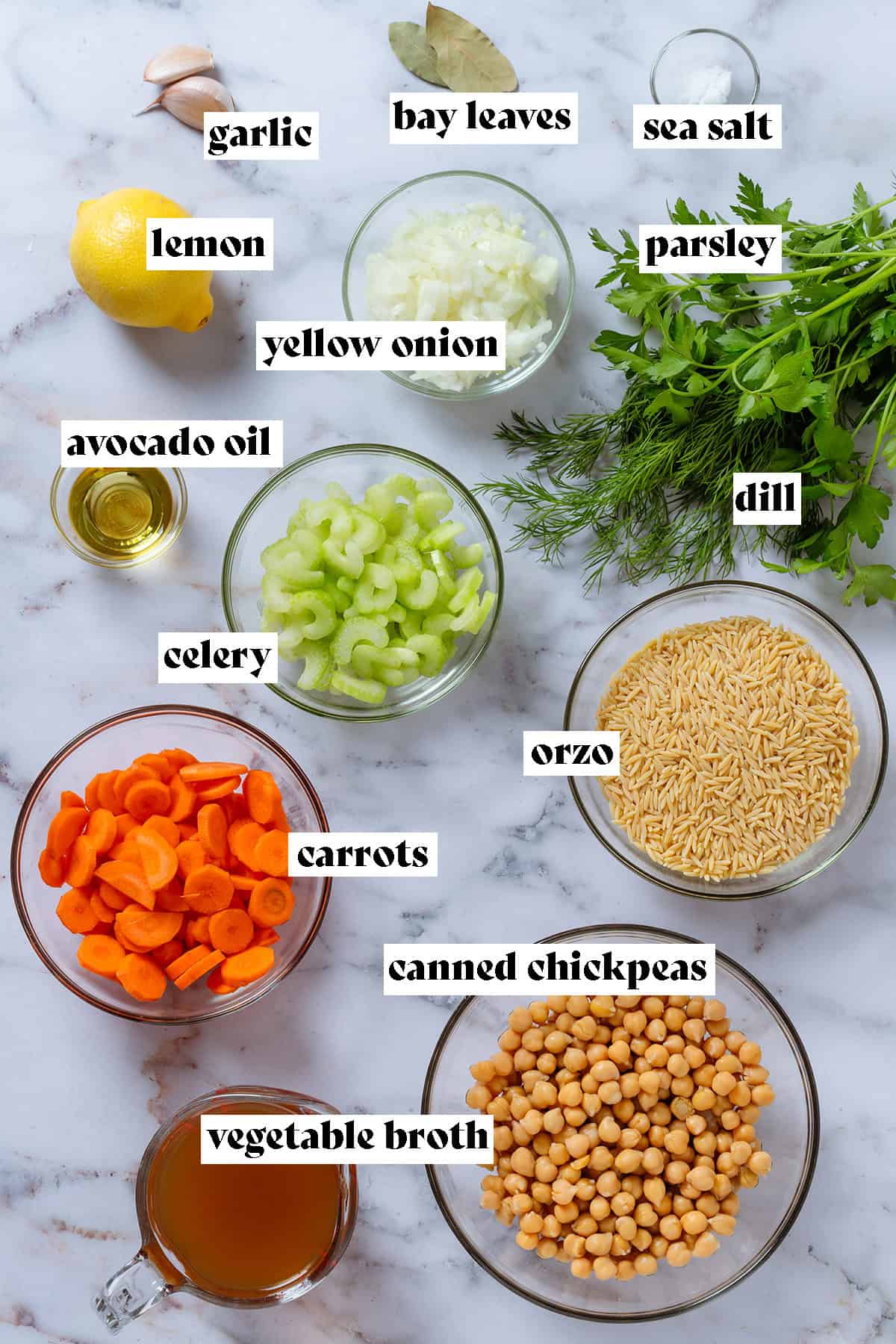 Glass bowls with ingredients like orzo, canned chickpeas, celery, carrots, and yellow onion.