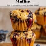 Two blueberry chocolate chip muffins stacked on a small wooden cutting board.