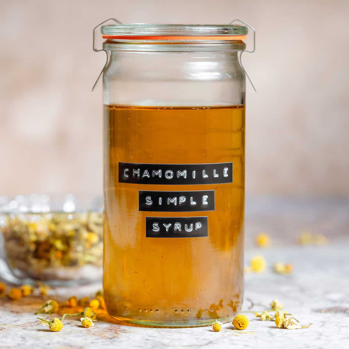 Golden chamomile simple syrup in a tall glass jar with an embossed label.