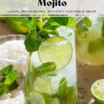 Two tall glasses with coconut mojito garnished with fresh mint leaves, a lime slice, and a glass straw with shredded coconut, limes, and mint in the background.