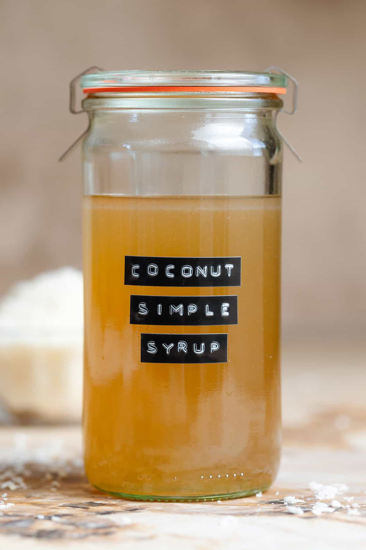 Coconut simple syrup in a tall glass jar with a black embossed label.