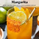 Bright orange mango margarita with ice in a short glass with a tajin rim, garnished with a slices of lime and mango, and with a gold straw.
