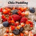 Creamy chocolate protein chia pudding in a white bowl garnished with fresh berries, maple syrup, and seeds with a spoon in the bowl.