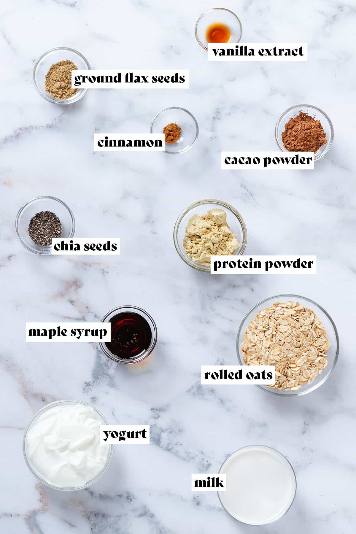 Small glass bowls with ingredients like oats, maple syrup, milk, yogurt, and cacao powder with text overlay.