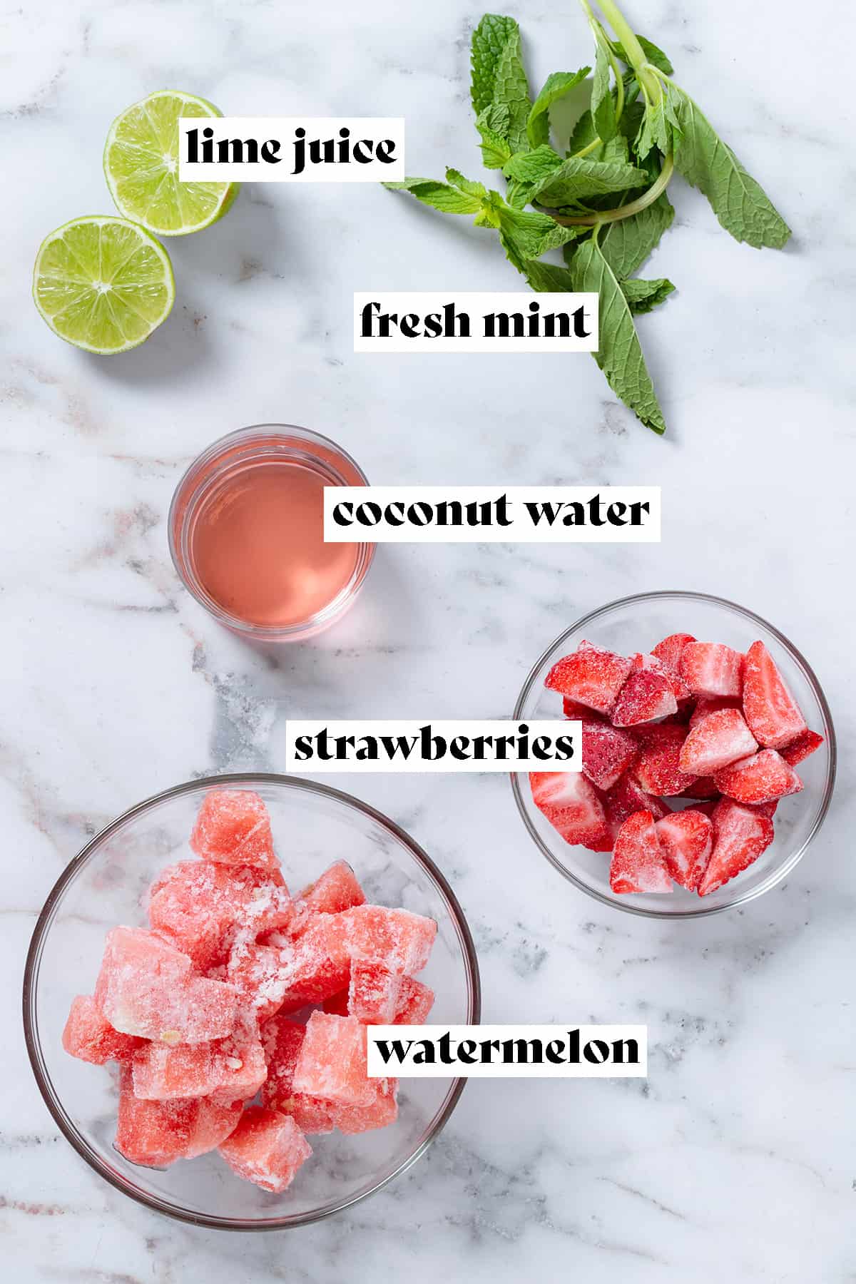 Glass bowls with frozen watermelon and strawberries and fresh mint, lime, and coconut water on a grey background with text overlay.