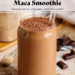 Creamy chocolate smoothie in a glass shaped like a soda can with a glass straw and garnished with grated chocolate with chocolate squares around the glass.