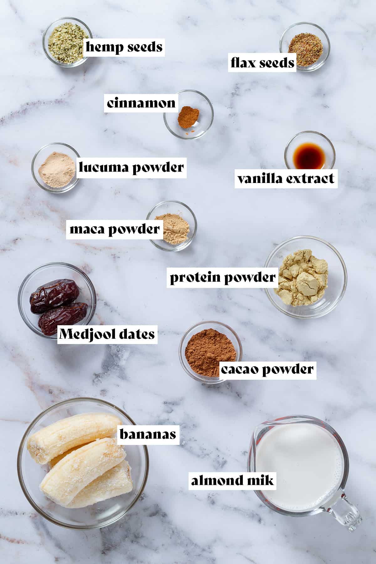 Ingredients like milk, frozen bananas, protein powder, maca, cacao, and lucuma powders, Medjool dates, and cinnamon in small glass bowls with text overlay.