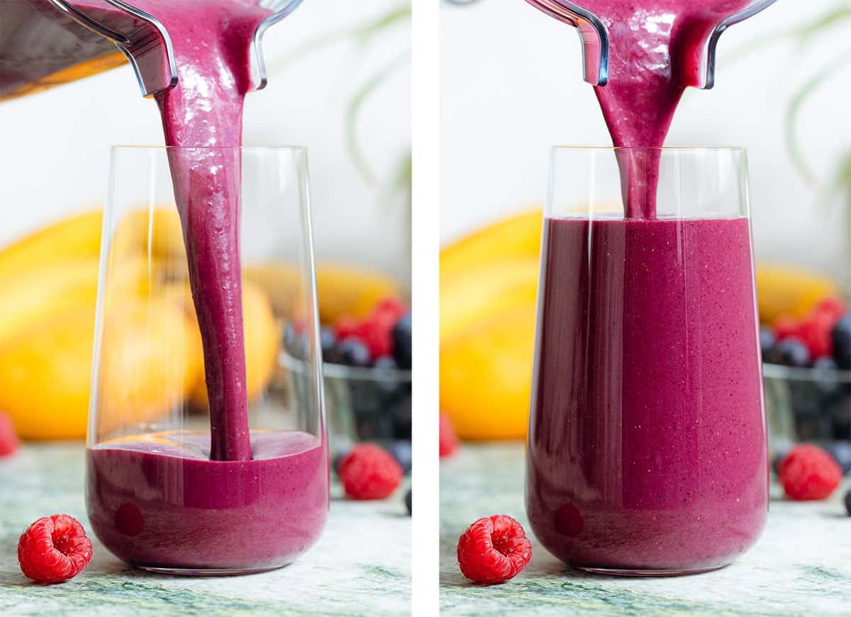 A bright purple berry smoothie being poured into a tall glass from a blender container.