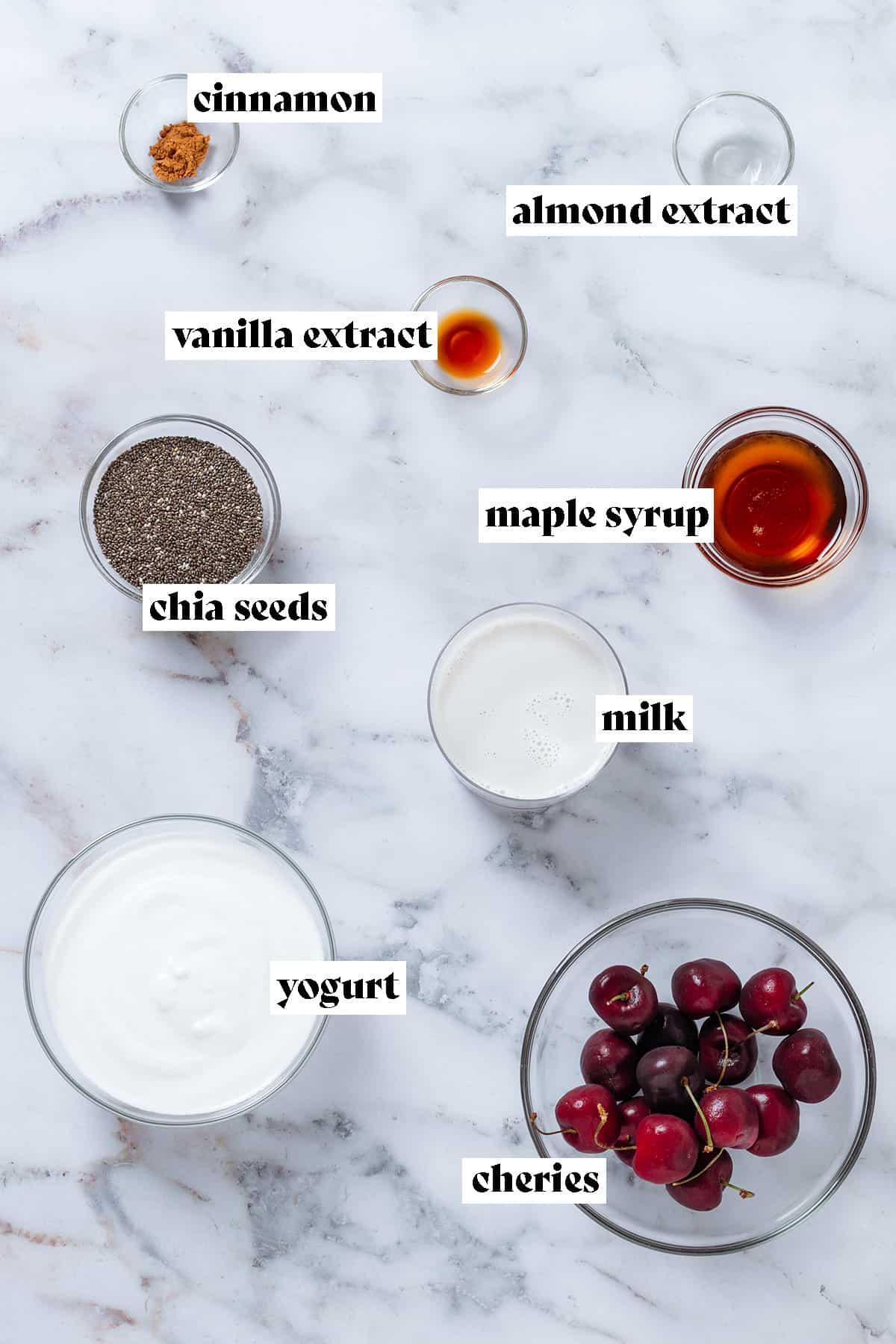 Ingredients in glass bowls like chia seeds, cherries, yogurt, milk, maple syrup, and spiced with text overlay.