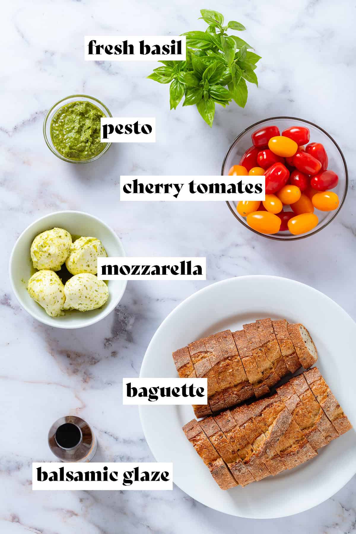 Ingredients like sliced baguette, mozzarella balls, cherry tomatoes, and fresh basil on a marble background with text overlay.