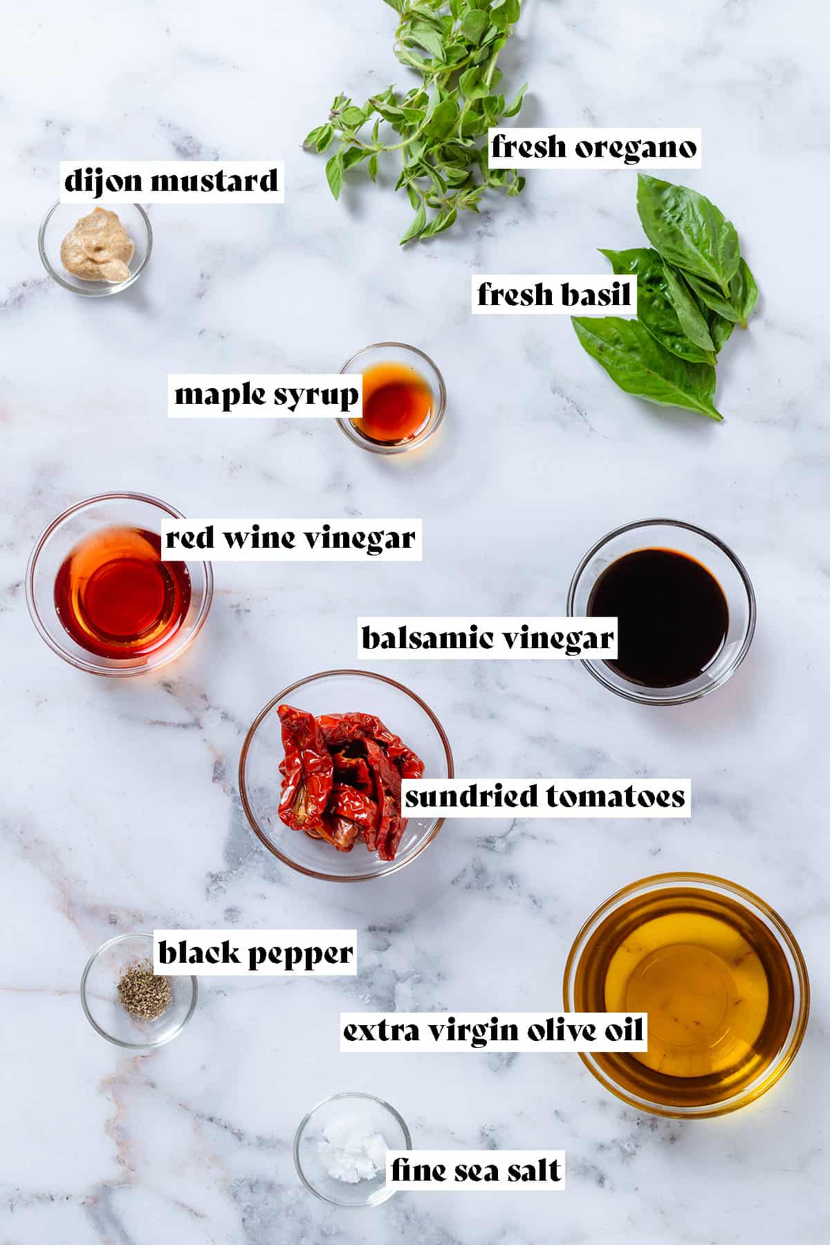 Glass bowls with ingredients like olive oil, vinegar, sundried tomatoes, and spices with text overlay.
